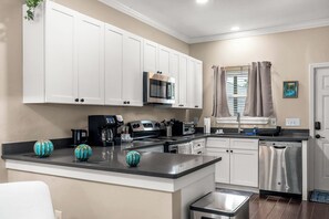 A modern kitchen with white cabinets, stainless steel appliances, and a central island.