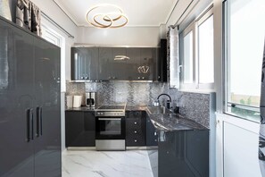 A modern kitchen with dark cabinetry, a built-in oven, and a large window. - Kalamata Coastal Nest, Modern Seaside Escape (Kalamata)