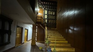 Un escalier en bois, doté d’une main courante, mène à un balcon orné d’une balustrade à motifs.
