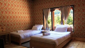 Une chambre avec deux lits simples, un bureau en bois et une fenêtre avec des rideaux.