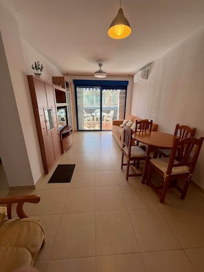 Una cocina amplia con comedor, un puerta corredera de vidrio que da a un balcón y un ventilador de techo.