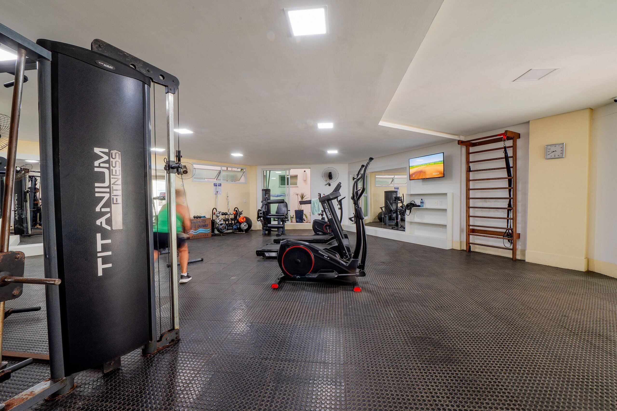 Et fitnessrum med en Titan Fitness-maskine, løbebånd og en pull-up bar.