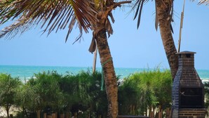 Blick auf einen Strand mit einem Backstein-Barbecue und Palmen.