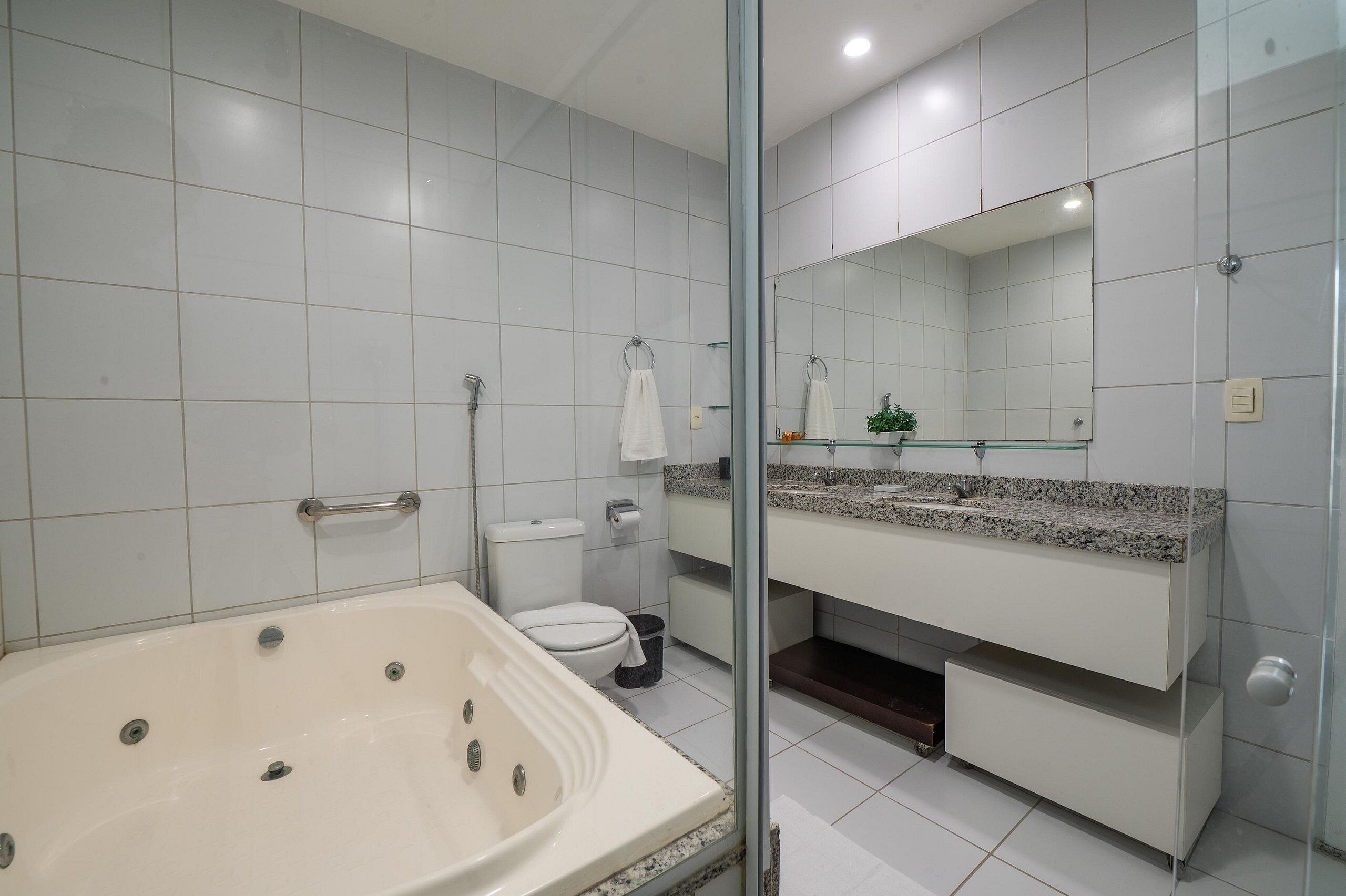A modern bathroom with a bathtub, toilet, and vanity with a mirror.
