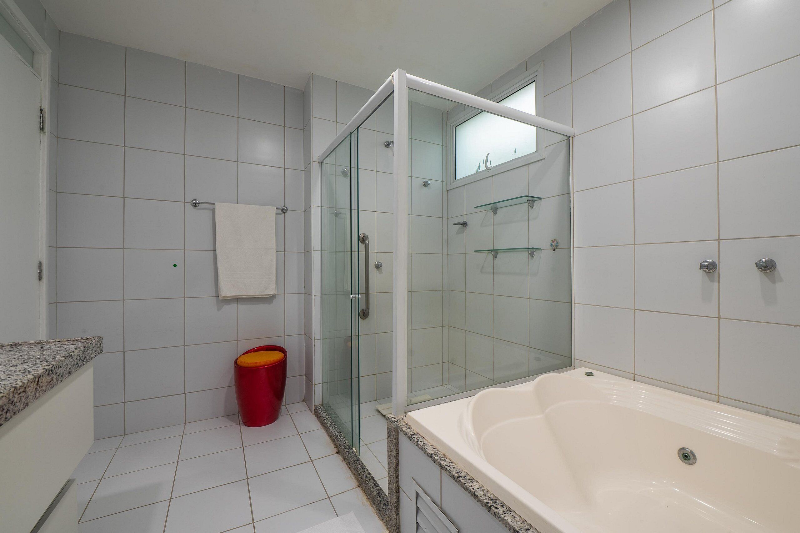 Un baño moderno con ducha envuelta en vidrio, una bañera blanca y encimera de granito.