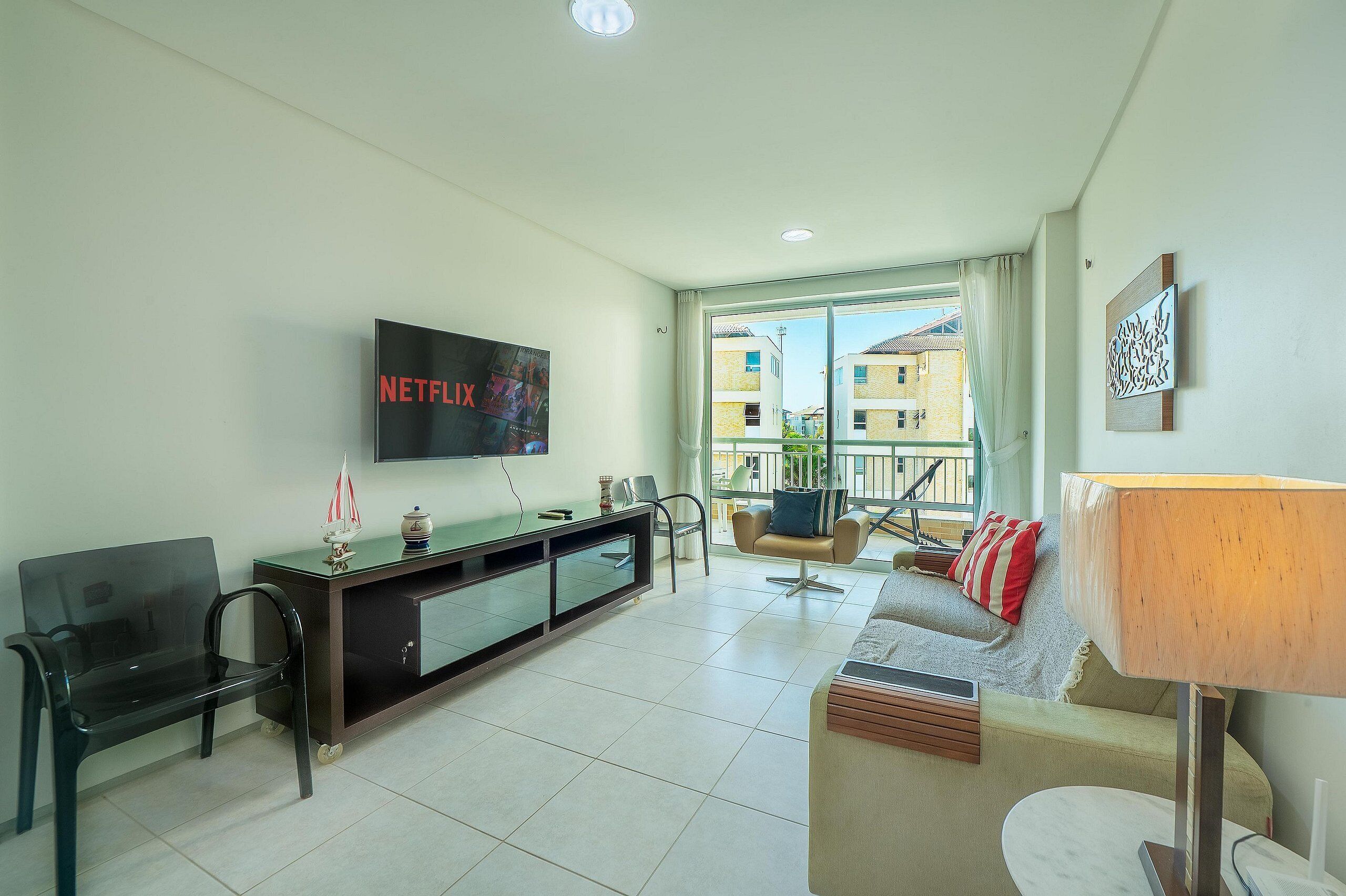 Una sala de estar moderna con una televisión de pantalla plana, un sofá, una mesa de centro y un mueble de televisión con adornos.