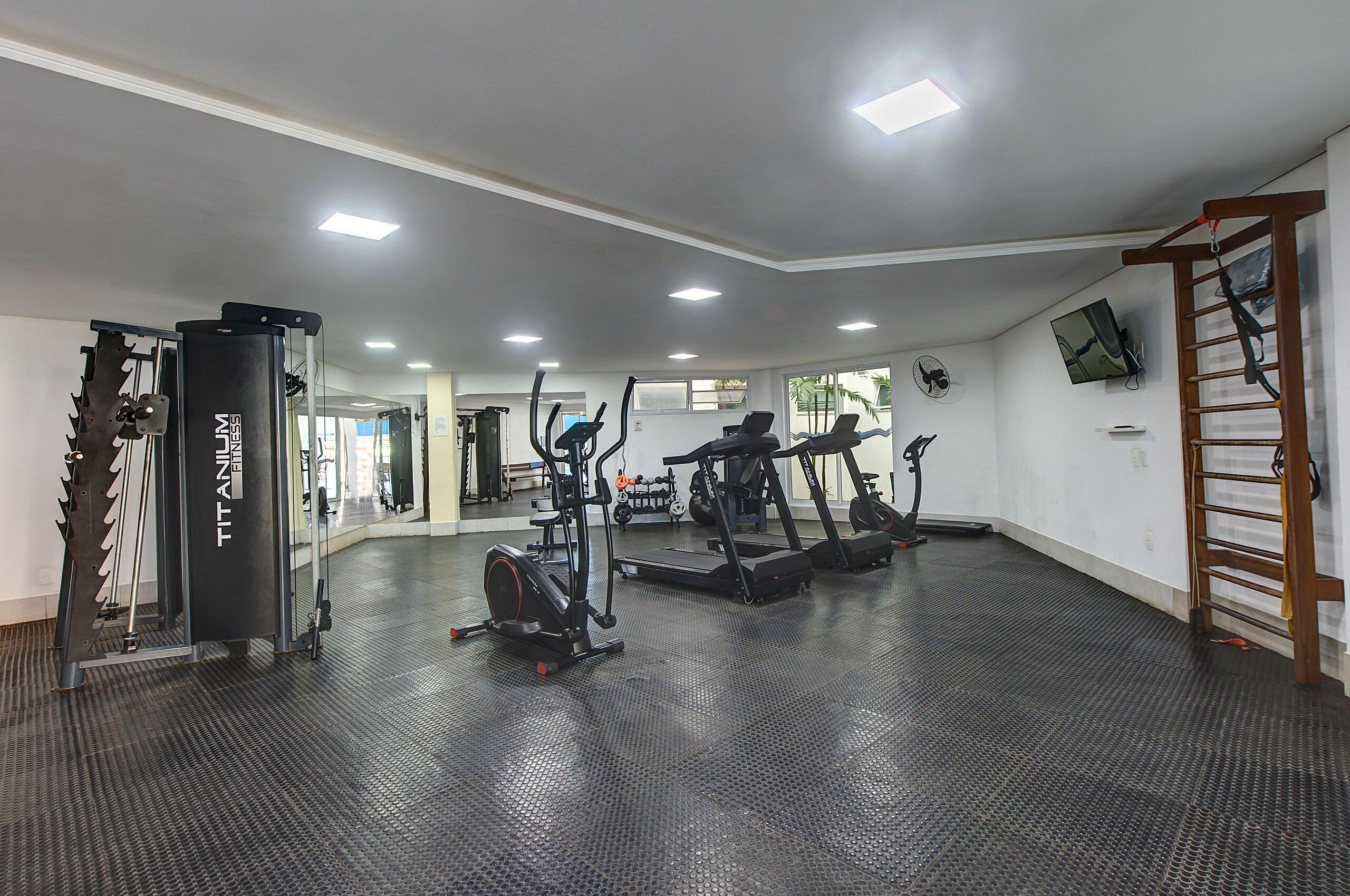 Un gimnasio con diversos equipos de ejercicio, como cintas de correr y una bicicleta estática.