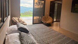 Ein Schlafzimmer mit einem großen Bett, einem Deckenventilator und Blick ins Freie.