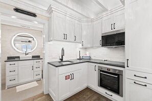 Une cuisine moderne avec des meubles blancs, un four encastré et un four à micro-ondes.