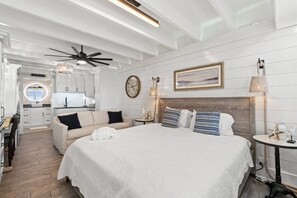 A hotel room with a large bed, a sitting area with a sofa, a dining area, and a kitchen. - Gulf-Front Beachfront Condo w/ Pool | Walk to Dini (Panama City Beach)