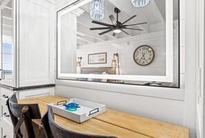 Een moderne keuken met witte kasten, een houten eettafel en een groot raam met uitzicht op het interieur.
