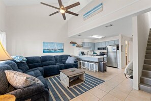 A modern living room with a sofa, coffee table, and a painting of a sailboat. - Pet-Friendly 2BR | Walk to the Beach | Pool (Panama City Beach)