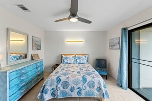 A bedroom with a bed, a dresser, a ceiling fan, and a sliding glass door. - Pet-Friendly 2BR | Walk to the Beach | Pool (Panama City Beach)