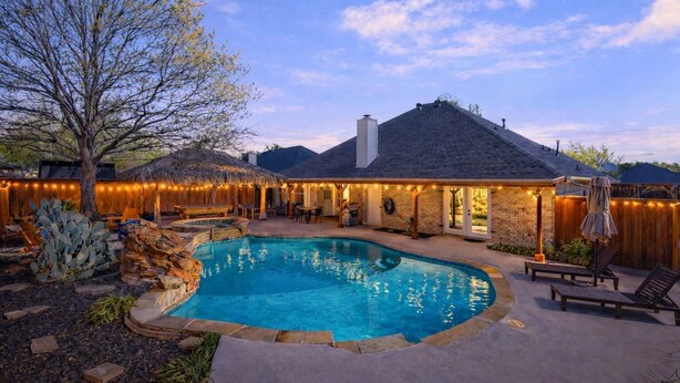 Un jardin avec une piscine, un espace barbecue et une terrasse couverte.