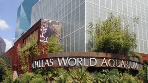 L’enseigne du Dallas World Aquarium, avec un grand bâtiment en verre en arrière-plan.