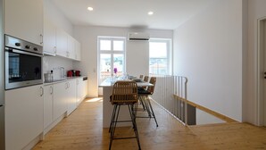 A modern kitchen with white cabinets, a built-in oven, and a dining area with a wooden table and chairs.