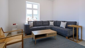 A modern living room with a grey sectional sofa, a wooden coffee table, and a small side table.