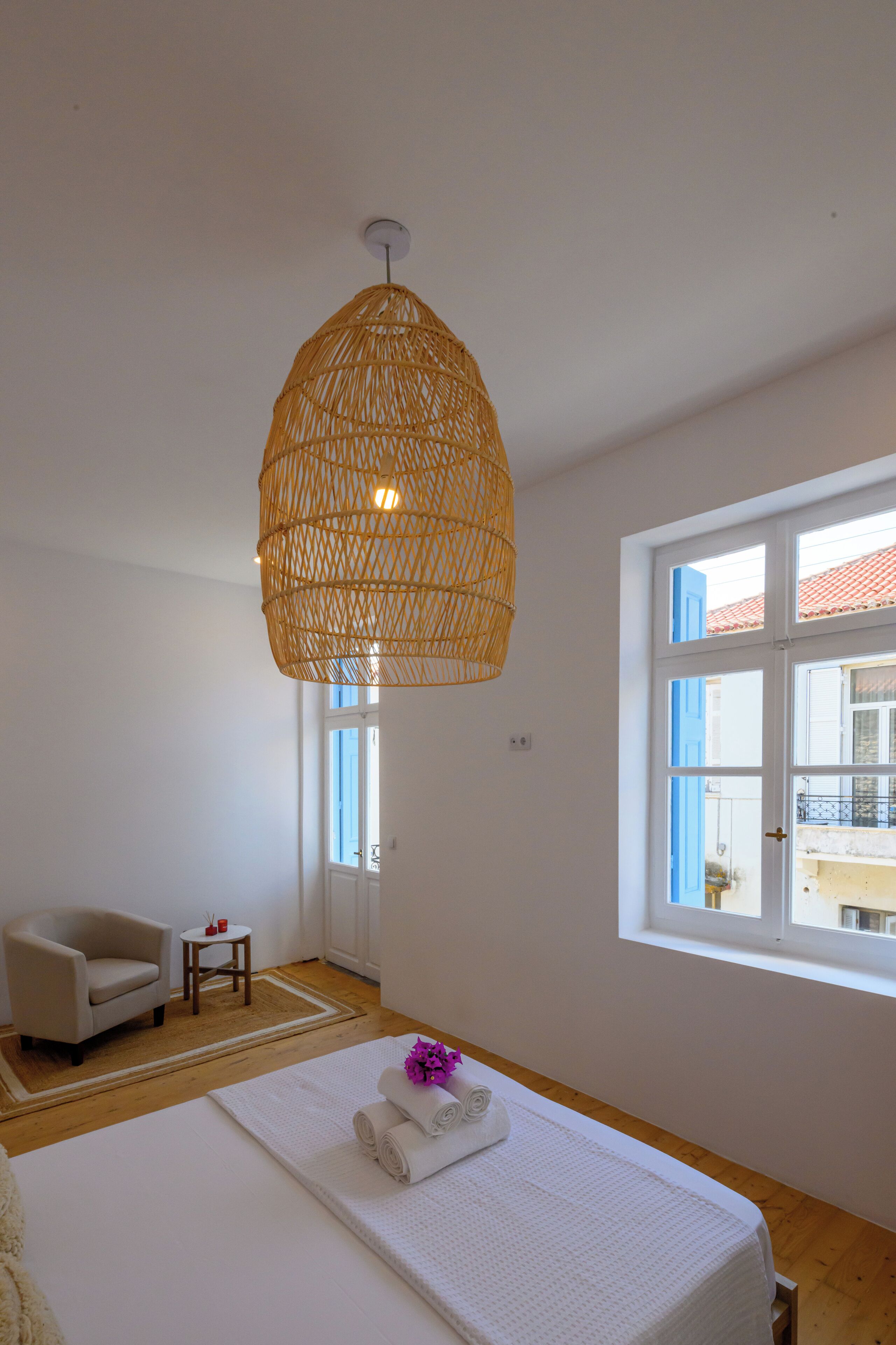 Une chambre à coucher comprenant un lit, une chaise, une petite table et un luminaire suspendu.