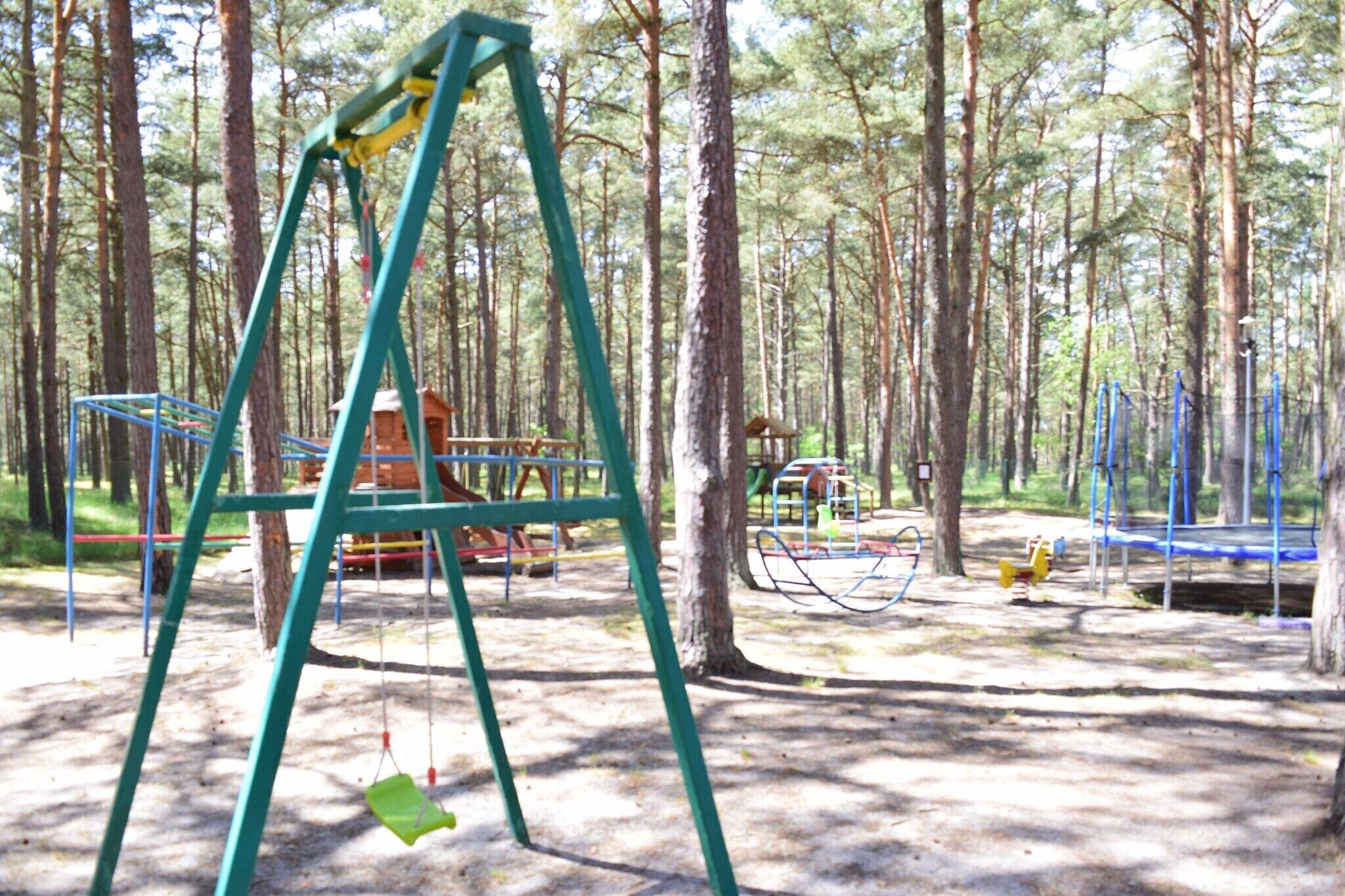 A playground with swings and climbing structures in a wooded area.