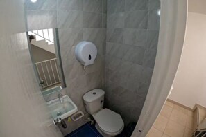 Ein kleines Badezimmer mit Toilette, Waschbecken und einem Händetrockner.