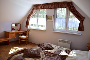 A bedroom with a bed, a desk, a chair, and a window with curtains.