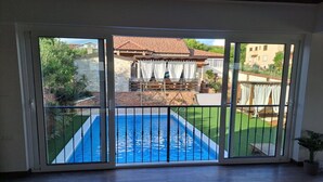 Habitació amb una gran porta corredissa de vidre que dona a un pati d'entrada amb piscina, zona de terrassa i vista a edificis veïnals.