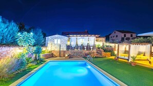 Una piscina amb un mur de maó i un jardí ben cuidat.