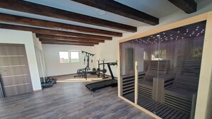 Una àmplia sala de gimnàstica amb sòl de fusta, bigues al sostre i equip d'exercici.