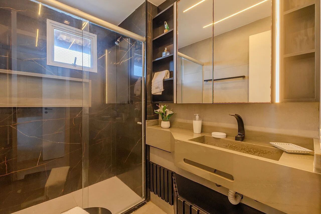 Un baño moderno con cabina de ducha de vidrio, tocador con lavabo y espejo.