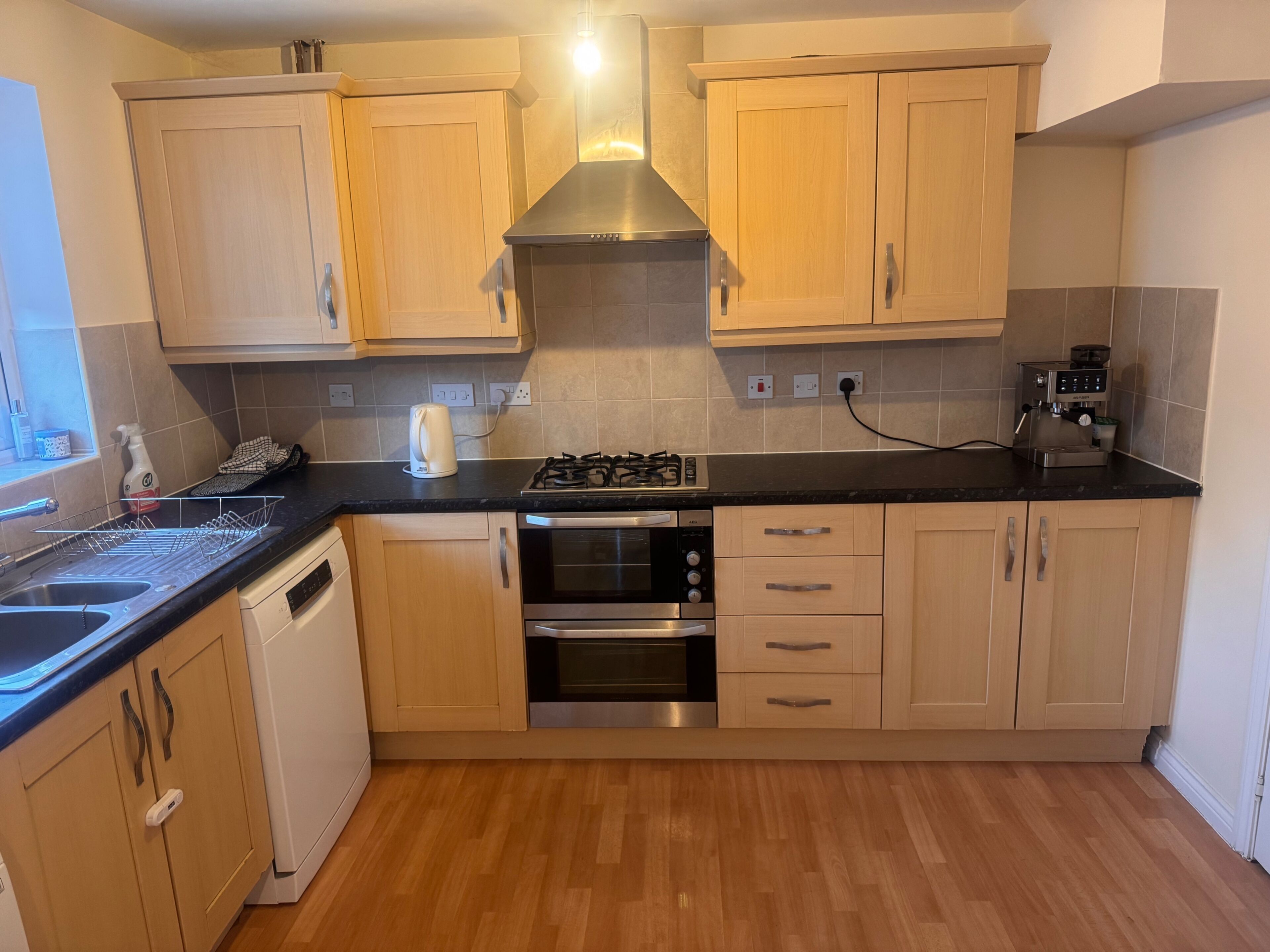 A kitchen with wooden cabinets, a gas stove, an oven, and a coffee machine.