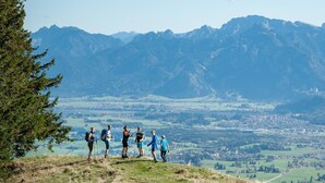 Um grupo de caminhantes em uma trilha de montanha, com vista para um vale e um lago.