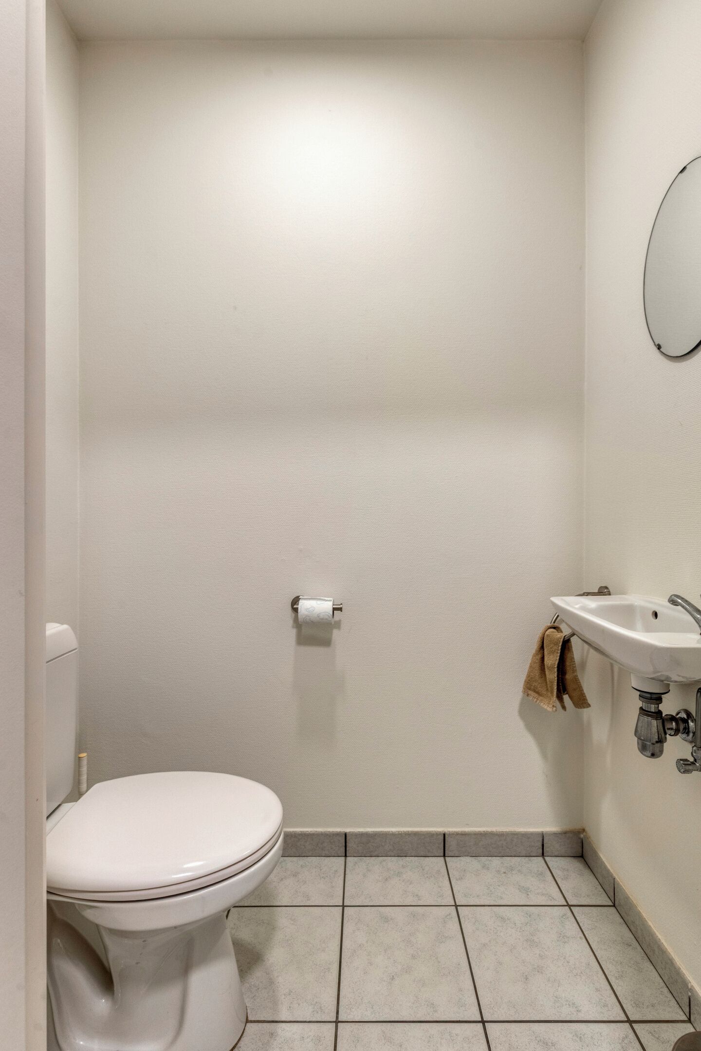 Ein kleines, sauberes Badezimmer mit Toilette, Waschbecken und Spiegel.