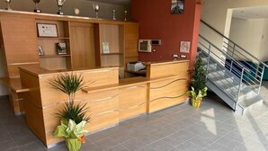 Ein Empfangsschalter mit Holzoptik, einem digitalen Bildschirm und einem gerahmten Zertifikat an der Wand.