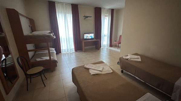 Une chambre d’hôtel avec des lits superposés, un canapé, une télévision et une chaise.