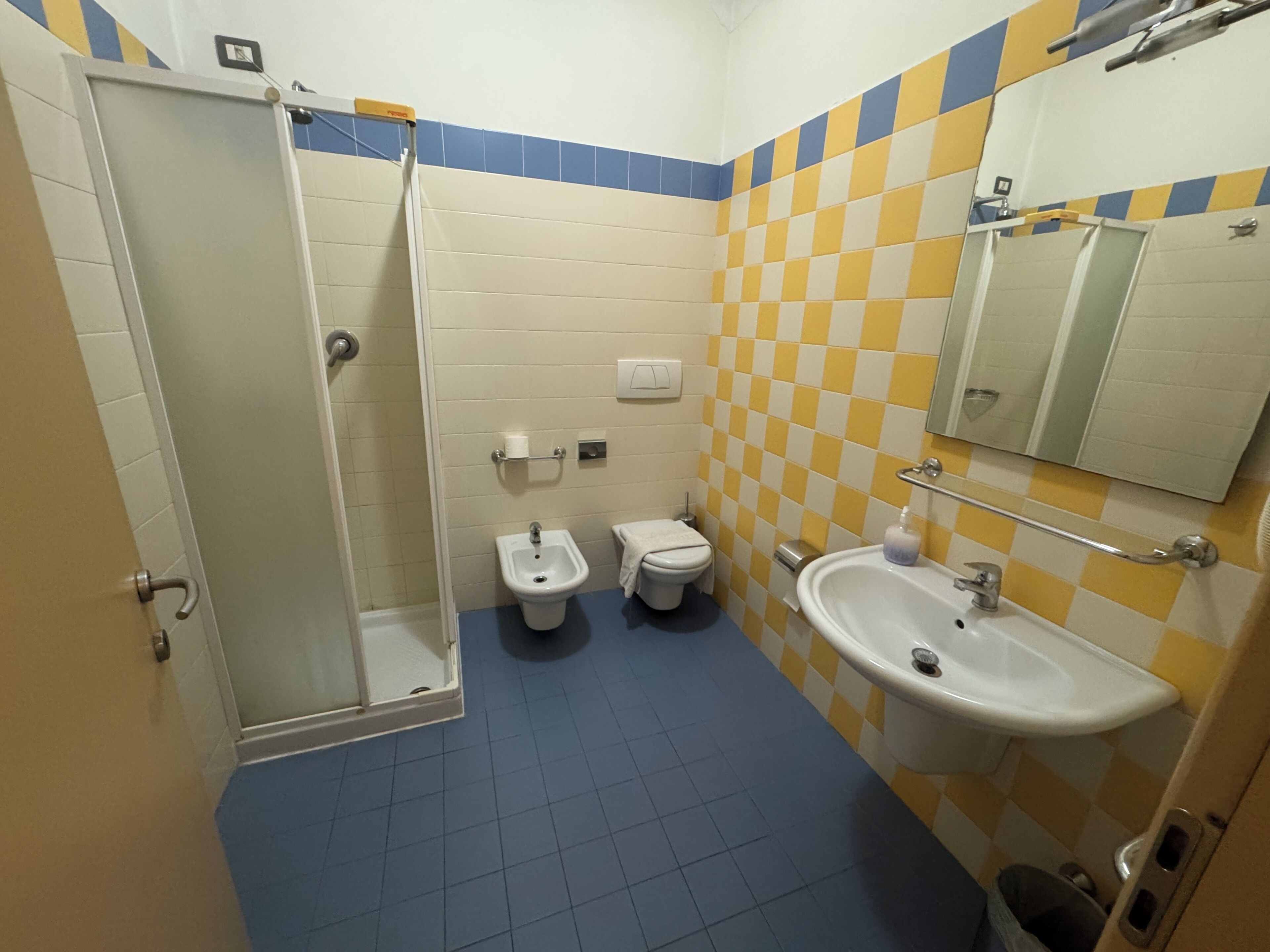 A bathroom with a shower, bidet, toilet, sink, and mirror.