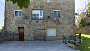 A stone building with three windows, a door, and a metal structure in the foreground. - La Casona de Ilusión (Solórzano)