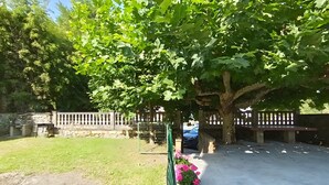 A paved patio area with a stone wall, a metal gate, and a bench. - La Casona de Ilusión (Solórzano)