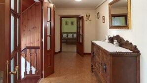A hallway with wooden doors, a mirror, and a dresser. - La Casona de Ilusión (Solórzano)