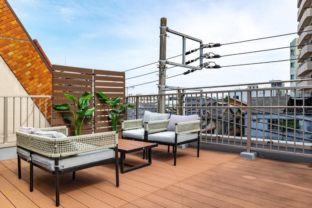 A rooftop terrace with wicker furniture, a metal railing, and potted plants.