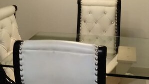 Un comedor con una mesa de vidrio y dos sillas tapizadas con detalles negros y blancos.