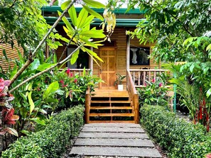 A wooden staircase leading to a wooden door, surrounded by lush greenery and plants. - Finca Los Mangos – 2 Eco Cabins w/ Pool (Manuel Antonio)