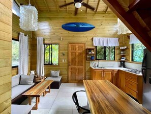 A wooden cabin interior with a dining area, kitchen, and seating space.
