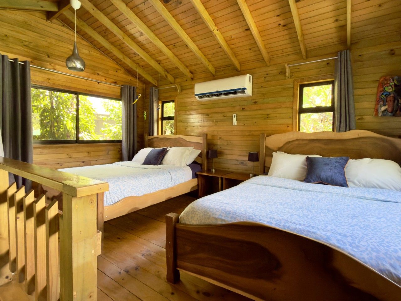 A cabin with two wooden beds, a wooden ceiling, and a window with curtains.