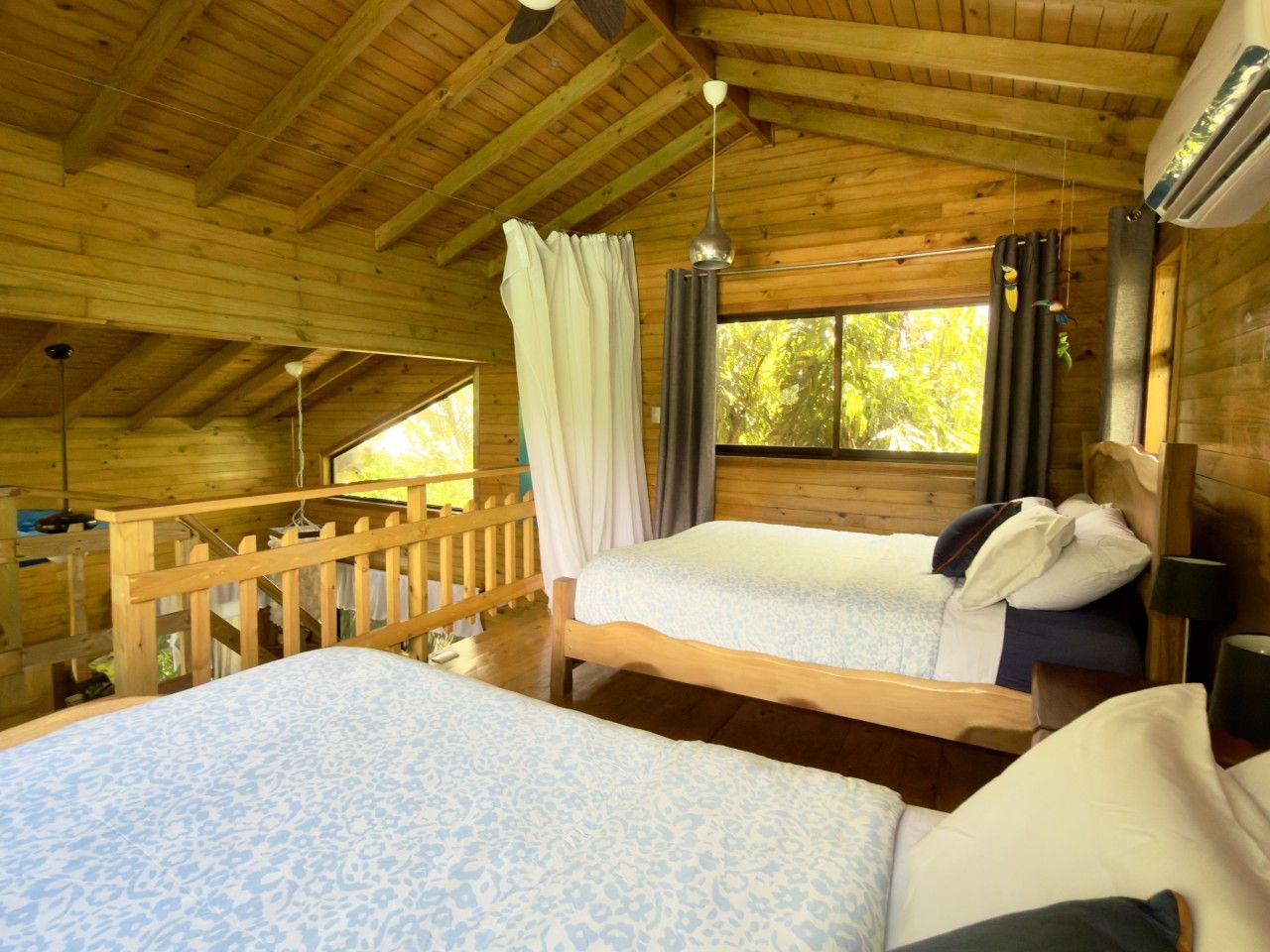 A wooden cabin bedroom with two beds, a window, and a ceiling fan.