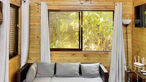 Una cabaña de madera acogedora con un ventanal grande, un sofá y un comedor.