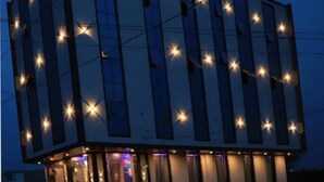 Et hotel med moderne design, der har en markant indgang med trapper og et skilt med teksten 'BIRLA PALACE'.