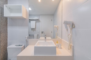 Een moderne badkamer met een witte wastafel, een haardroger en een handdoekhouder.