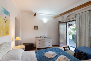A bedroom with a bed, two bedside tables, a dresser, and a view through a glass door.