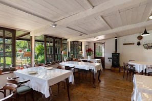 A dining area with tables set for meals, large windows, and a wooden ceiling.