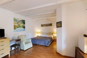 A bedroom with a bed, a desk, a chair, a television, and artwork on the walls.